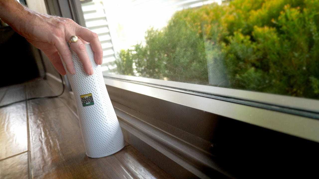 Air purifier in a living room with people on a couch and a television in the background.