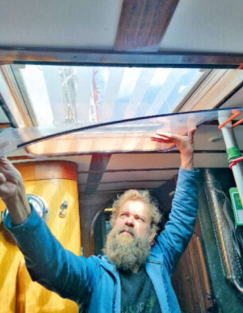 Person adjusting a large skylight inside a boat