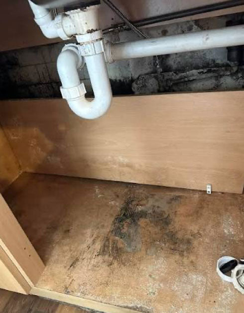 Underground plumbing system with pipes and a wooden floor.