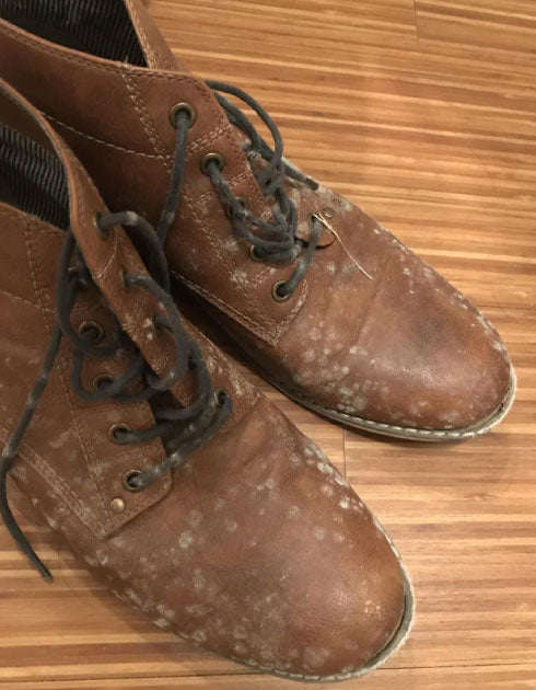 Pair of brown leather boots with black laces on a wooden floor.