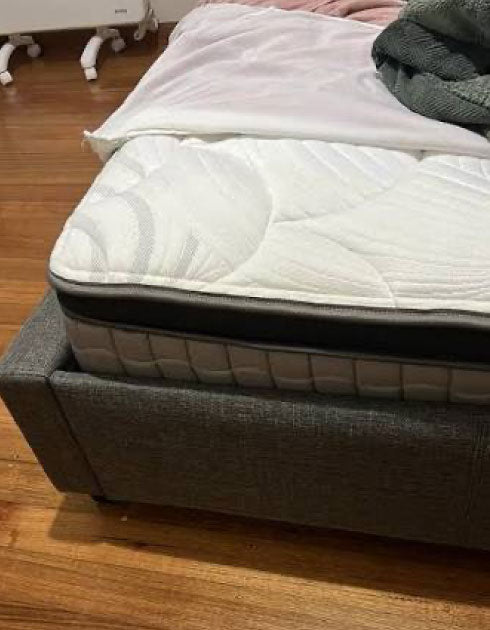 Bed with mattress and bedding on a wooden floor