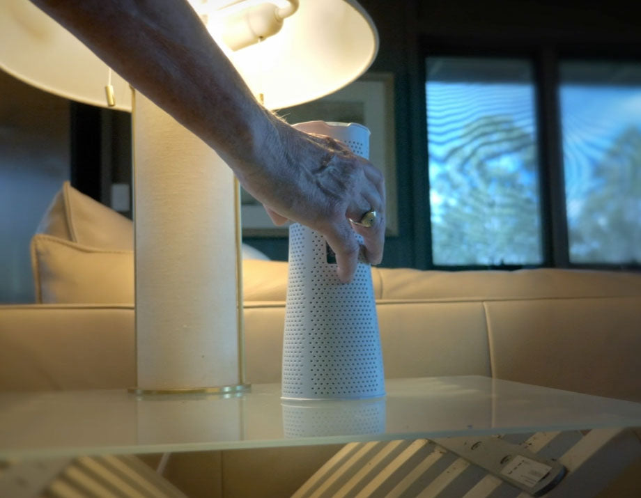 Person interacting with a white cylindrical object on a reflective surface