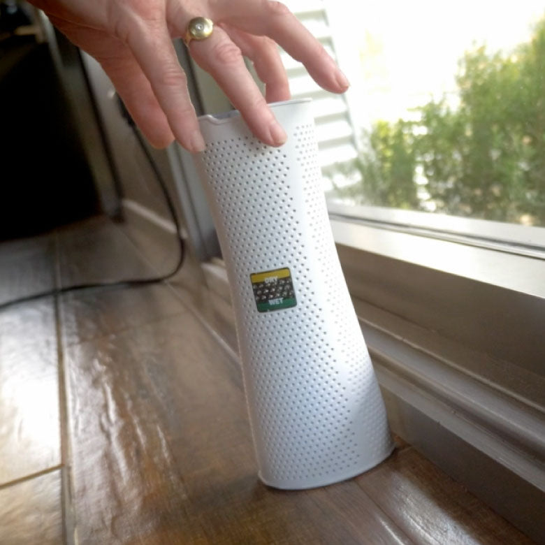 White Dry Styx tower on a windowsill with a hand reaching towards it